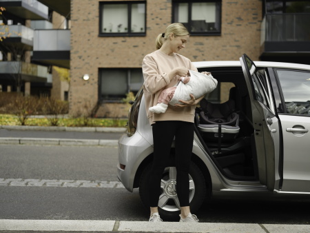 Mutter mit Baby in der Transfer vor dem Auto